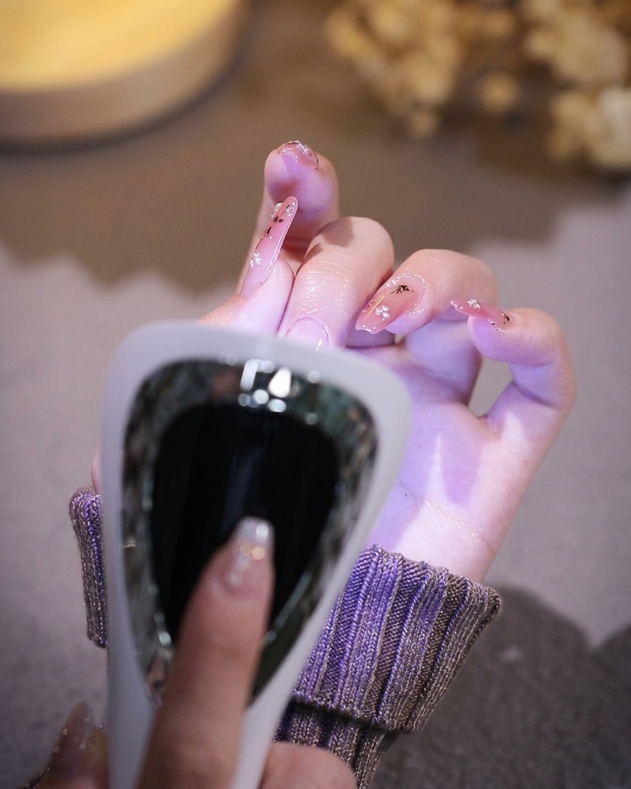 Eine Hand liegt zur Aushärtung des Gels in einer professionellen UV/LED-Lampe.