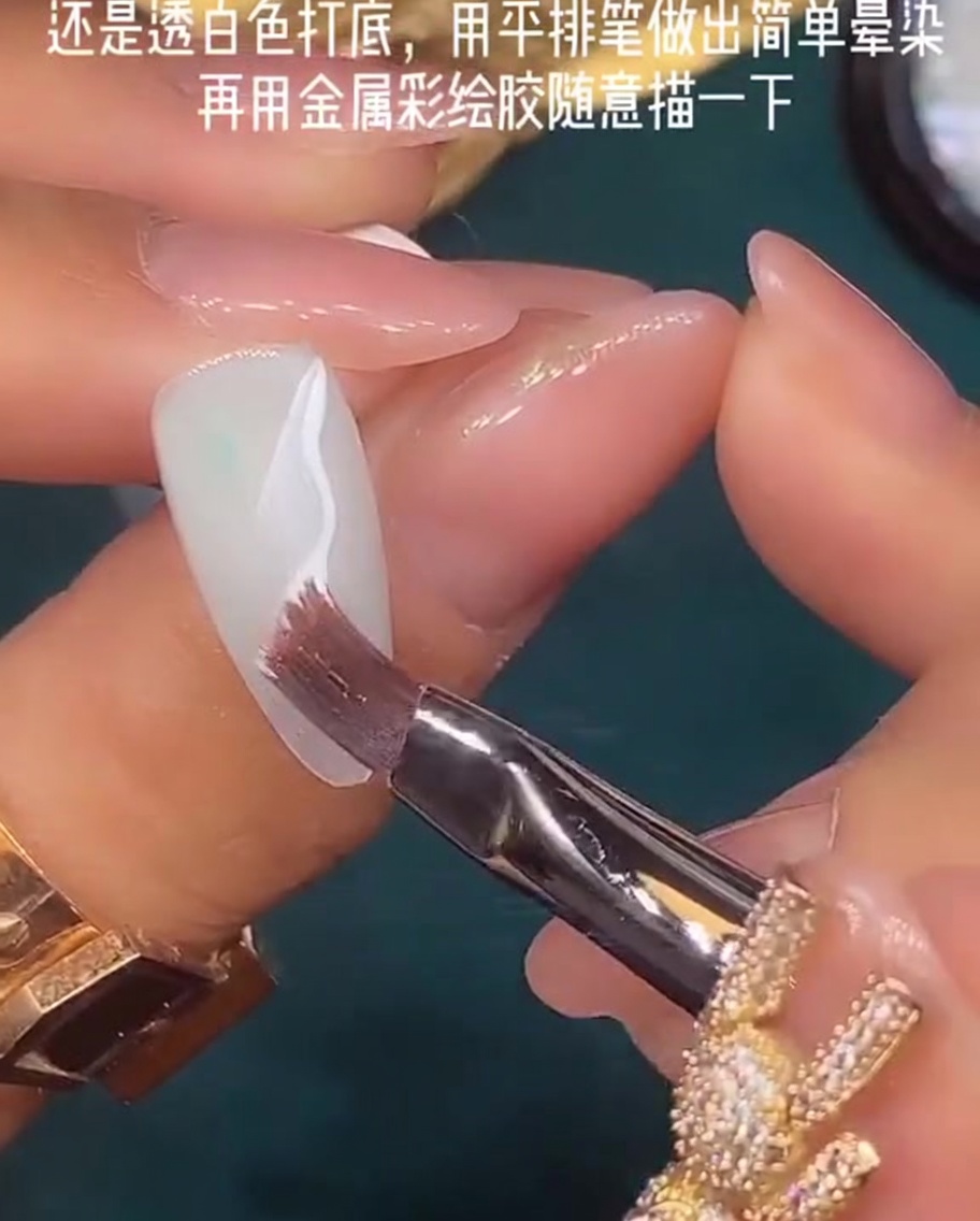 Ein flacher Nagelpinsel wird verwendet, um nasses weißes Gel auf einer Nageloberfläche zu verblenden.