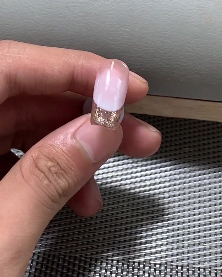 Eine Hand unter einer professionellen UV-Nagellampe beim Aushärten des Gel-Nagellacks.