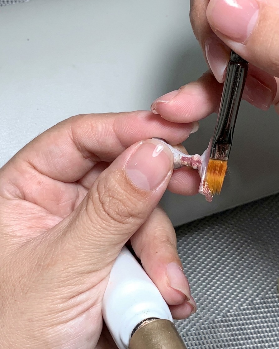 Eine Nagelfeile, die zum Glätten der ausgehärteten Nageloberfläche verwendet wird, bis sie glatt und ebenmäßig ist.