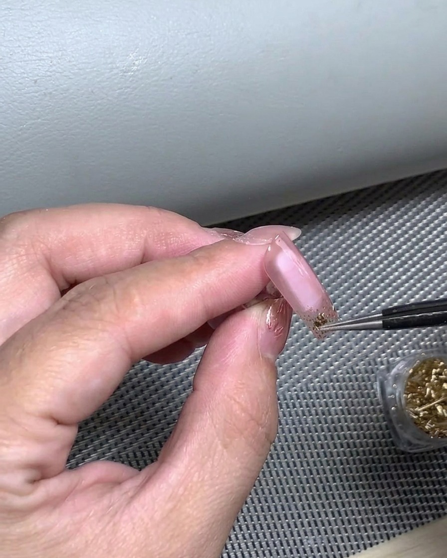 Ein Finger, der auf einen French-Tip-Nagelsticker drückt, um eine vollständige Haftung auf dem Nagelbett sicherzustellen.