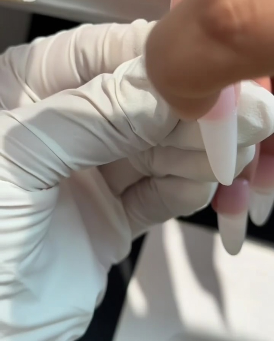 Ein Make-up-Schwämmchen tupft milchweißes Gel auf die Nagelspitze für einen Ombré-Effekt.