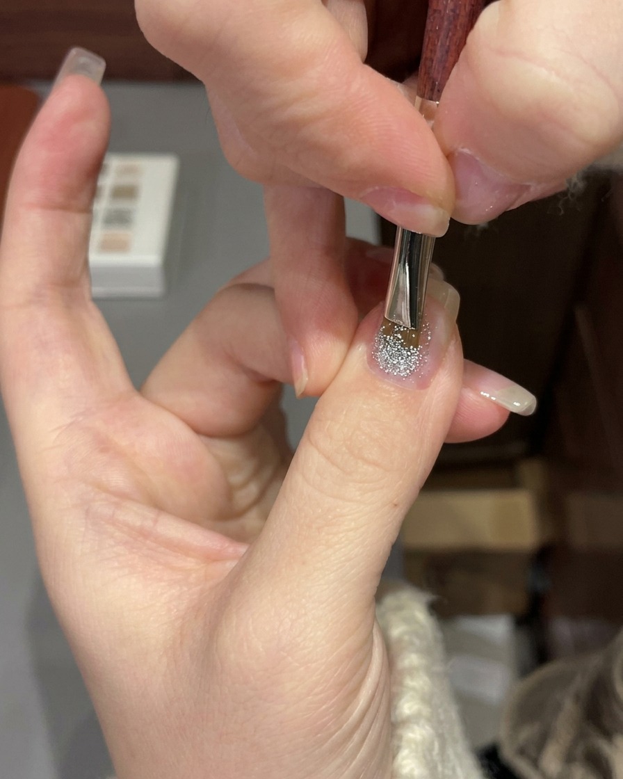 Eine Hand wird unter einer professionellen UV/LED-Lampe positioniert, um das Glitzergel auszuhärten.