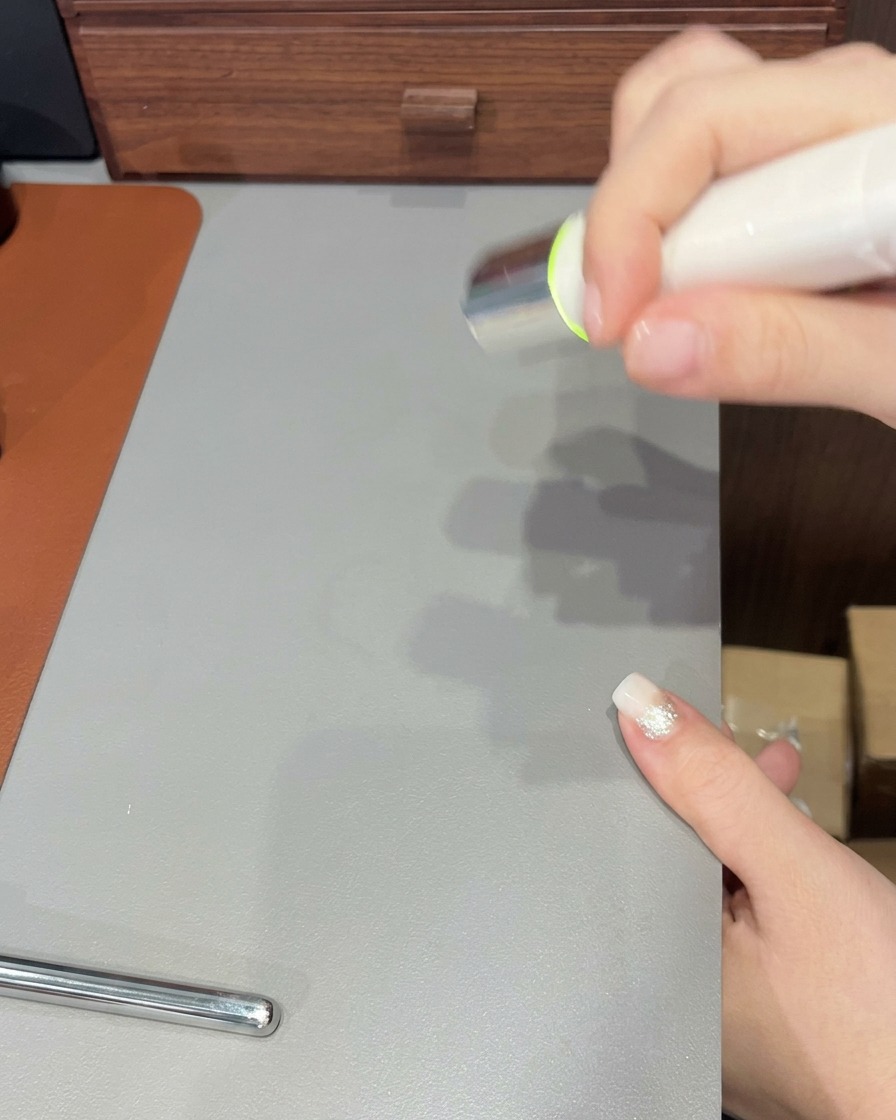 Ein Nagelpinsel trägt eine letzte, klare Gelschicht über einen fertiggestellten Ombré-Nagel auf.