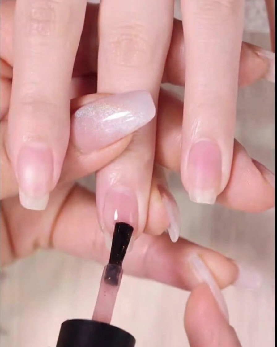 Ein Nagellackpinsel trägt dunkelbernsteinfarbenes Gel auf das obere Drittel der Nagelspitze auf.
