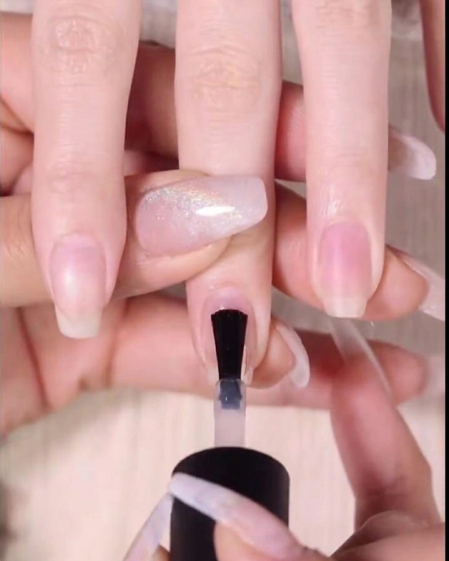 Eine Nahaufnahme, wie ein Pinsel rotes Gel auf die oberen zwei Drittel eines Nagels aufträgt.