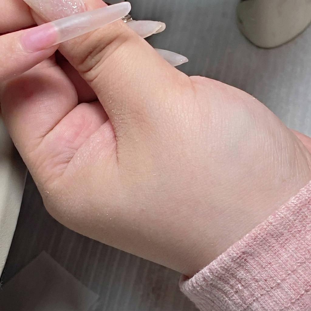 Ein Gel-Pinsel trägt klares Base Gel auf die Mitte der Nagelplatte auf.