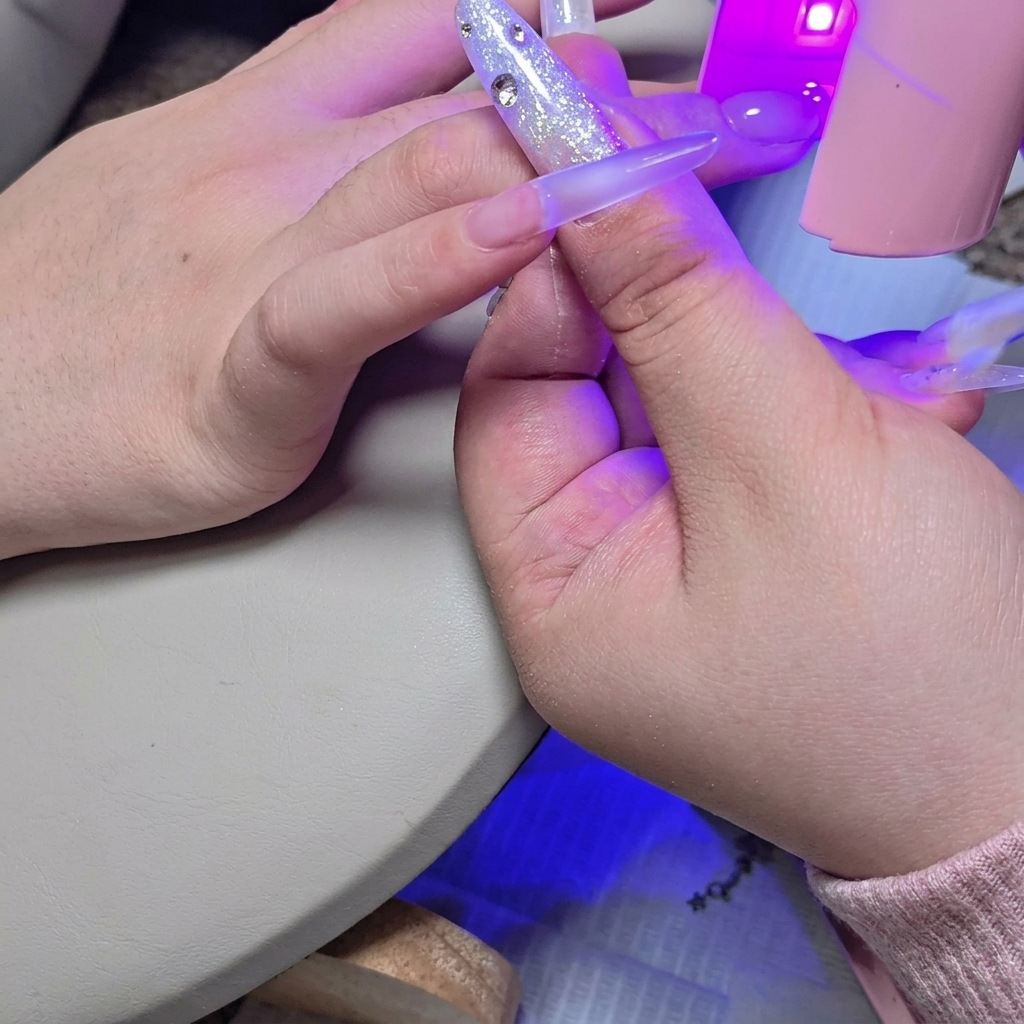 Eine kleine UV/LED-Lampe über dem Nagel zur Anhaftung der zweiten Gelschicht.