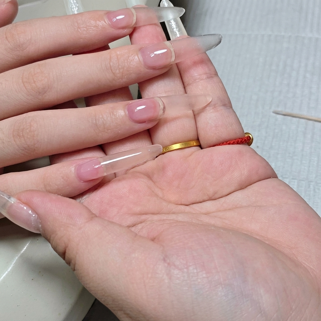 Seitenprofil eines fertig strukturierten, klaren Nagels mit Fokus auf die gleichmäßige Wölbung.
