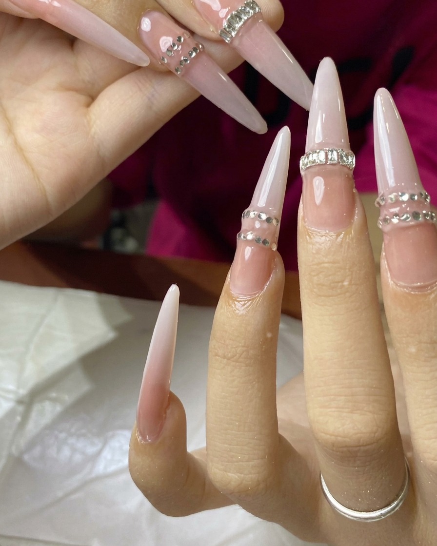 Eine Nahaufnahme eines Nagels, bei dem eine Reihe winziger Strasssteine aufgetragen und ausgehärtet wird.