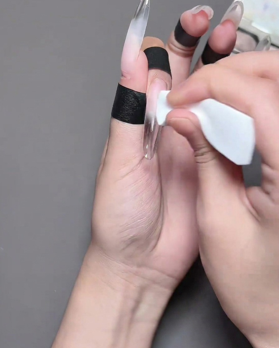 Nahaufnahme eines Fingers, bei dem schwarzes Barriere-Tape auf die Haut rund um die Nagelplatte aufgetragen wird.