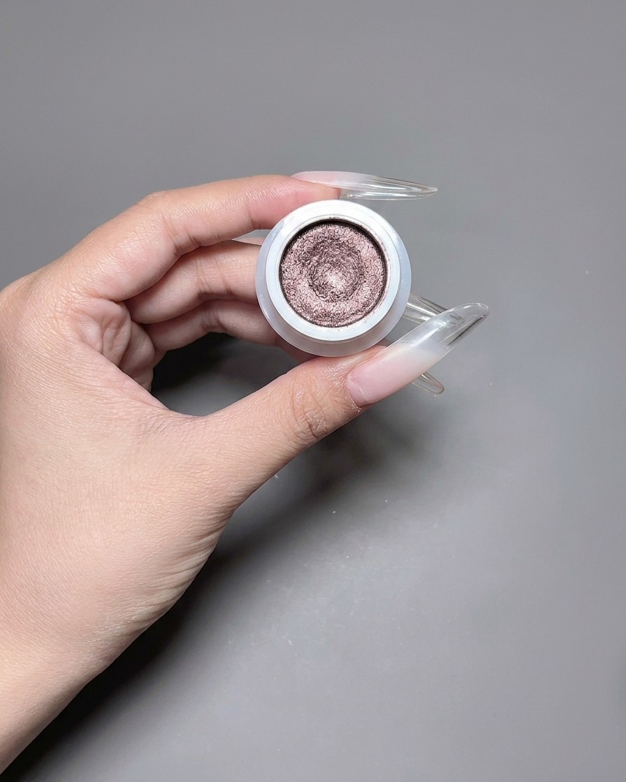 Ein Pinsel trägt ein reflektierendes, schimmerndes Cat-Eye-Gel auf einen langen Nagel auf.