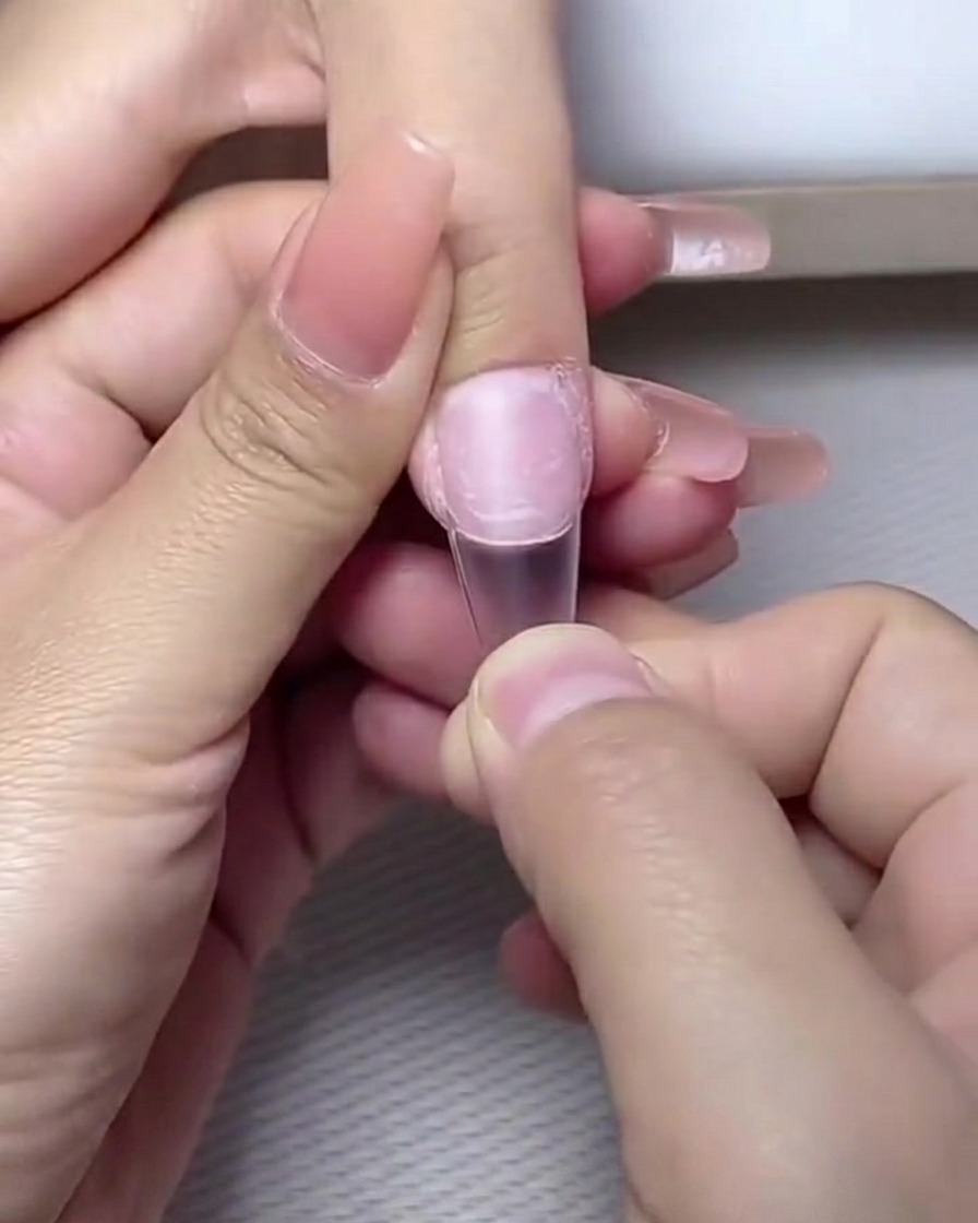 Finger in einer professionellen UV/LED-Nagellampe zum Aushärten.