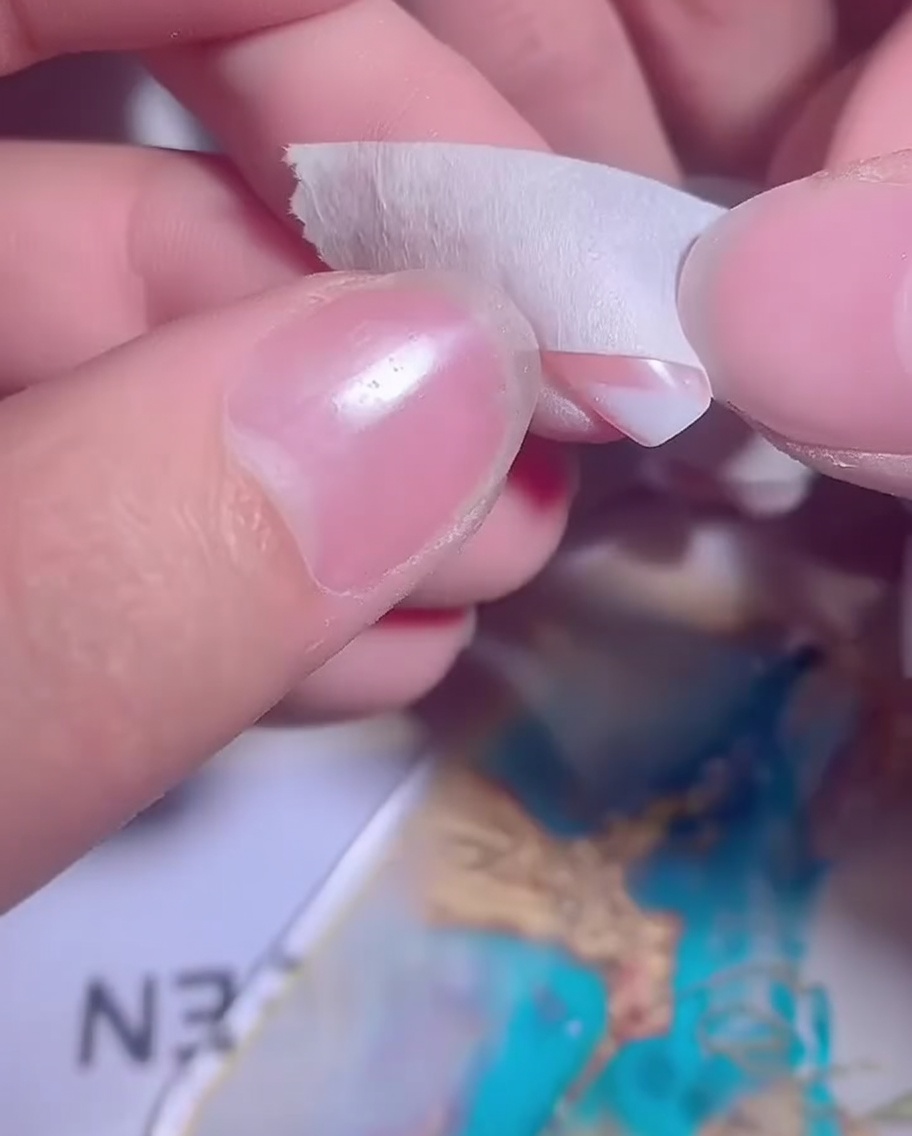 Ein Nagel mit einem teilweise aufgetragenen weißen Gel-Ombré wird für eine zweite Schicht vorbereitet.