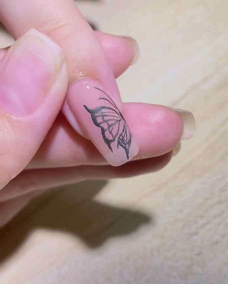 Nahaufnahme eines Nagels, auf dem mit einem silbernen Metallic-Liner-Pinsel ein Flammenmuster umrissen wird.