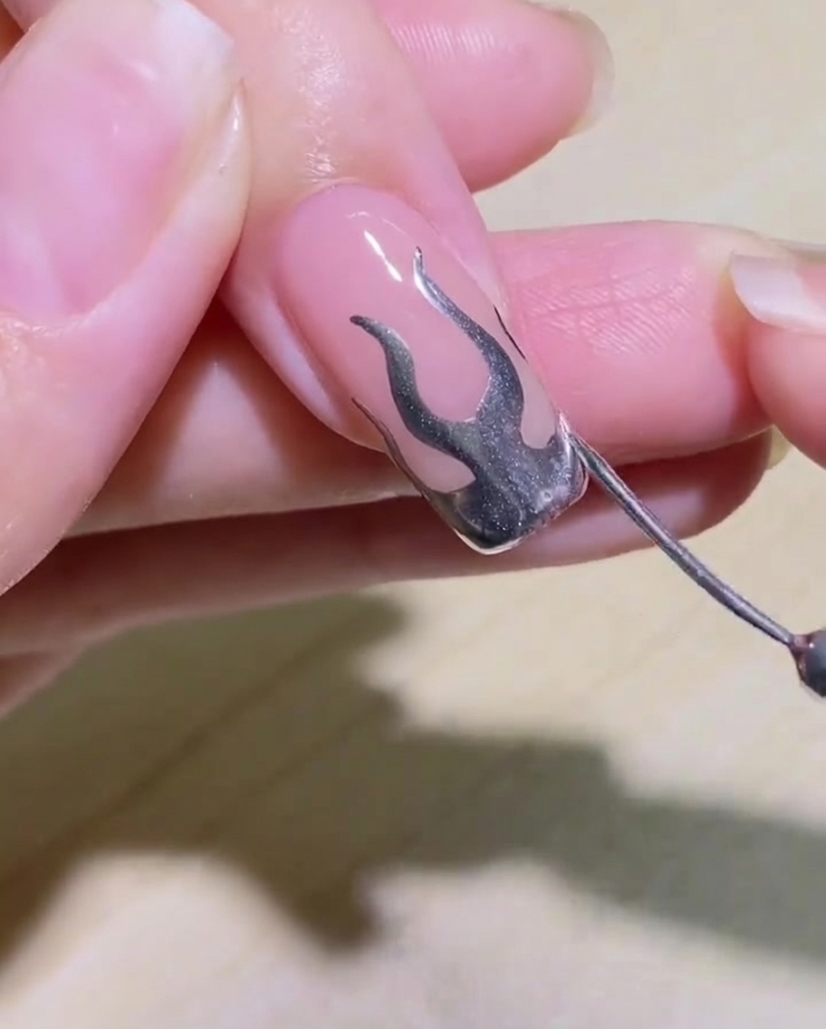 Detailaufnahme des fertigen Flammen-Nageldesigns, bevor es zum Aushärten unter die Lampe gelegt wird.
