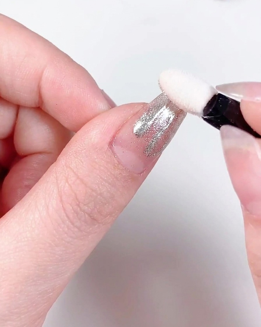 Nahaufnahme eines Fingers mit Chrom-bestäubten Flammenmustern, die unter einer professionellen UV/LED-Nagellampe aushärten.