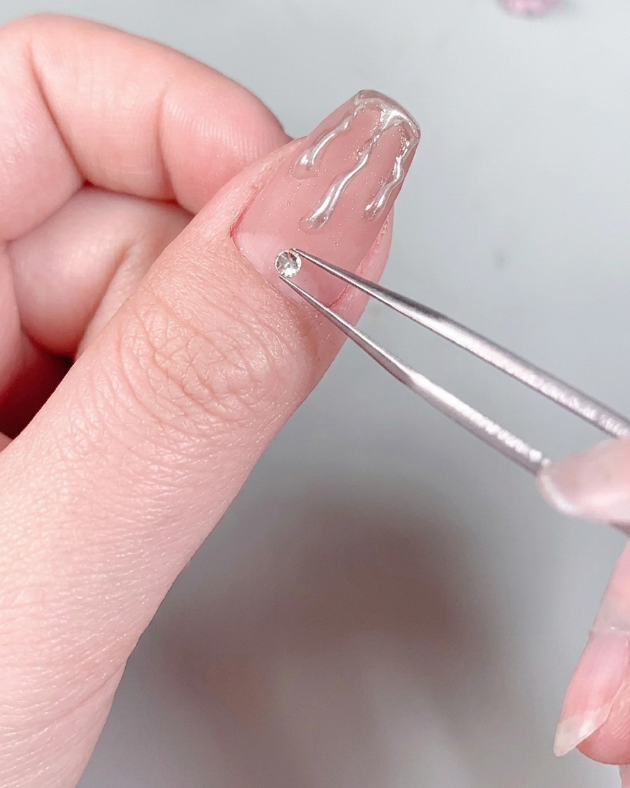 Ein manikierter Nagel mit einem Strassstein an der Basis wird unter das Licht einer UV/LED-Nagellampe gehalten.