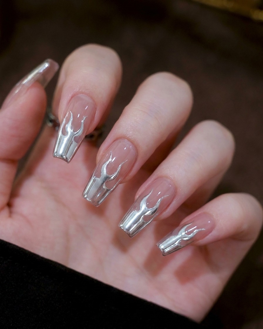 Nahaufnahme von zwei kleinen, symmetrischen U-förmigen Markierungen aus silbernem Gel in der Mitte eines Nagels.