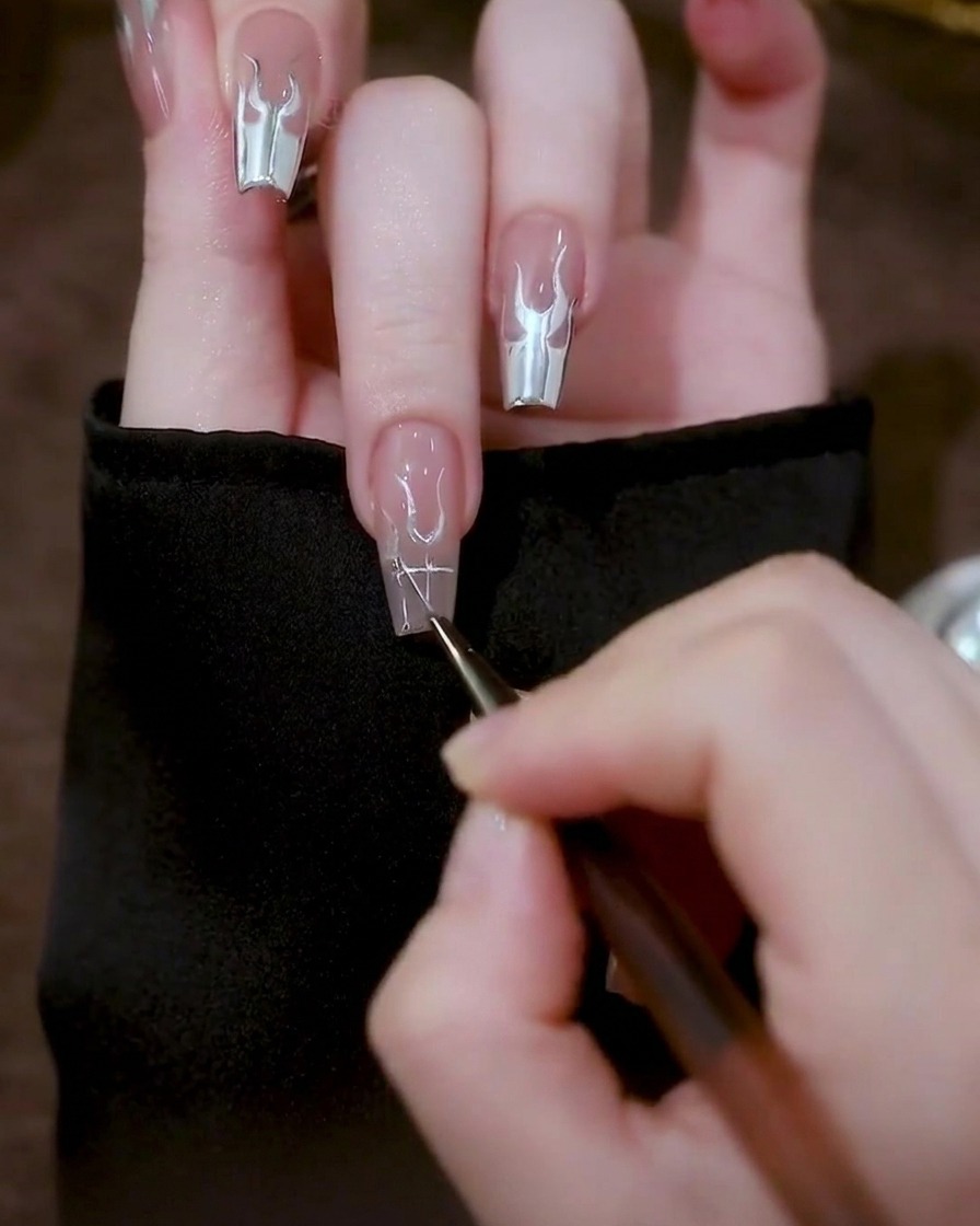 Nahaufnahme eines Nagels mit dreieckigen silbernen Gelformen auf beiden Seiten der zentralen U-Formen.