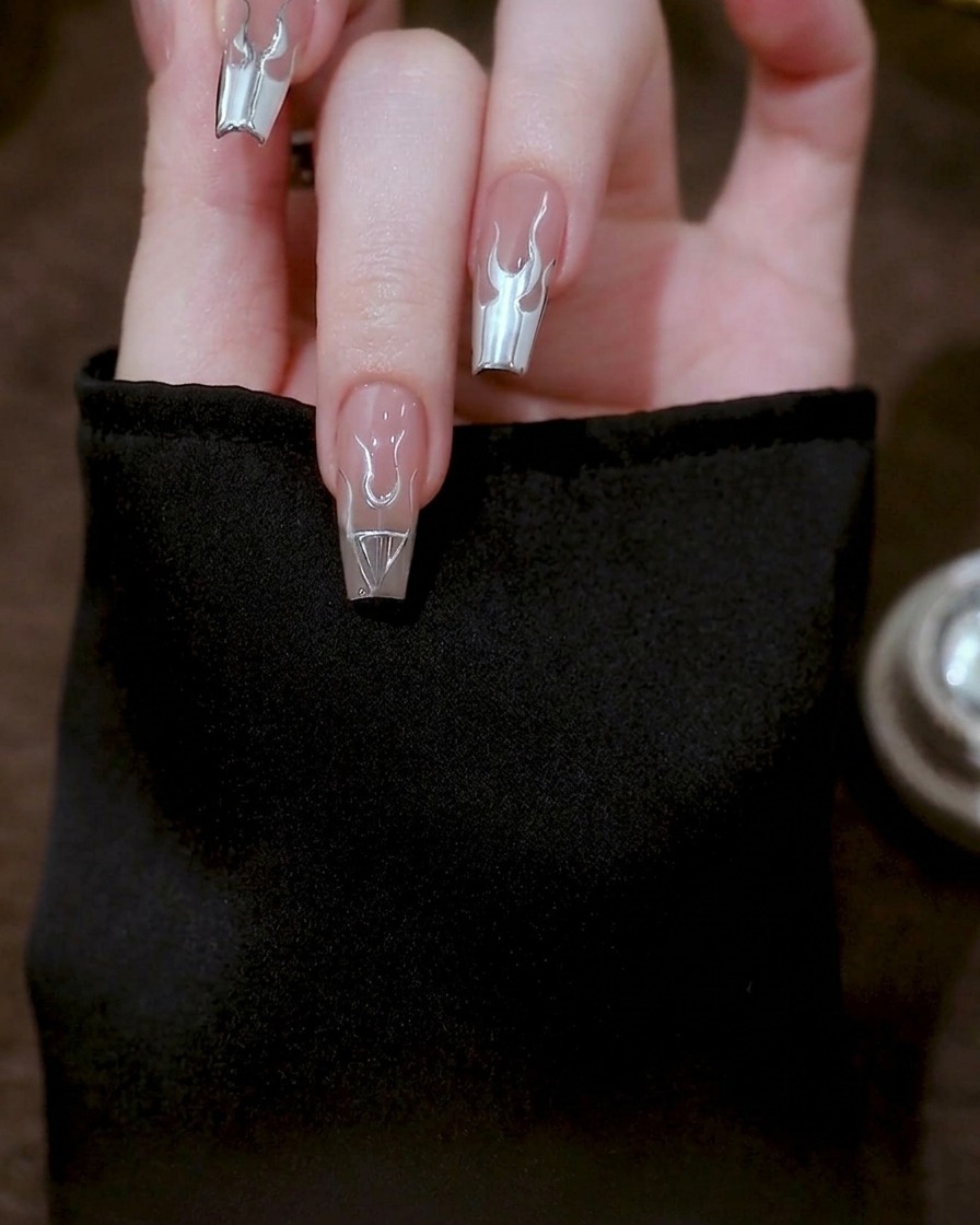 Nahaufnahme eines Nagels mit langen, geschwungenen silbernen Gellinien, die von der Flammenbasis bis zur Nagelspitze reichen.