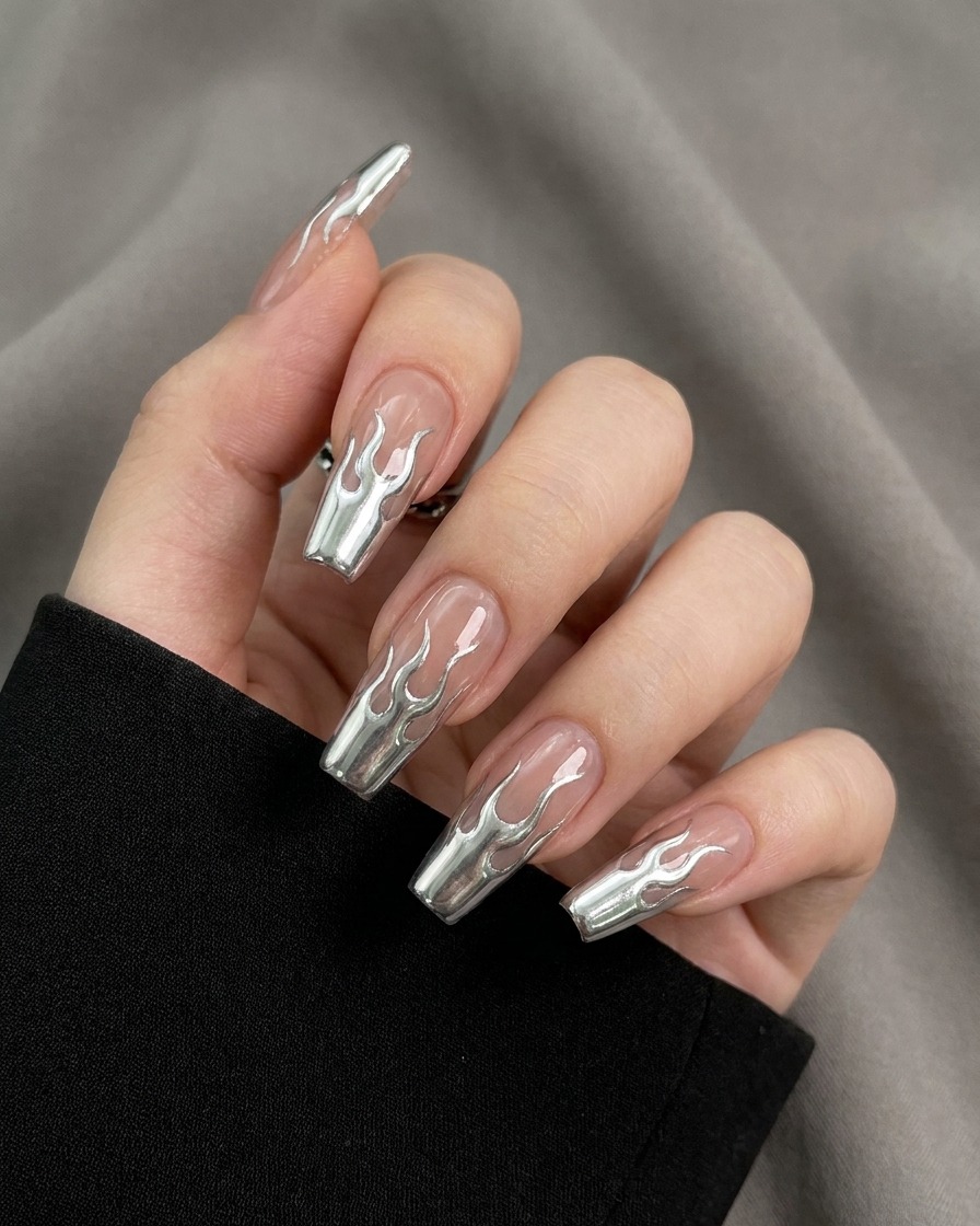 Nahaufnahme eines Pinsels, der die umrissenen Flammenformen auf einem Nagel mit hochreflektierendem Metallic-Silbergel ausfüllt.