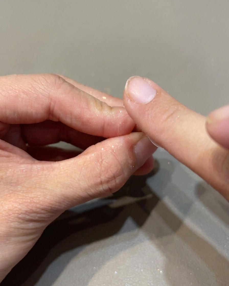 Ein kleiner Schwammapplikator reibt irisierendes Spiegelpuder auf einen Nagel für ein hochglänzendes Finish.