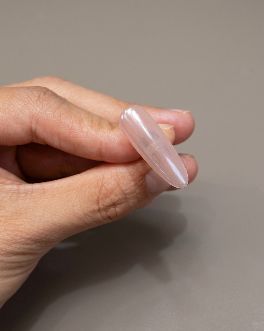Ein Pinsel trägt eine klare, schützende Gelschicht über einen Chrom-Nagel auf.