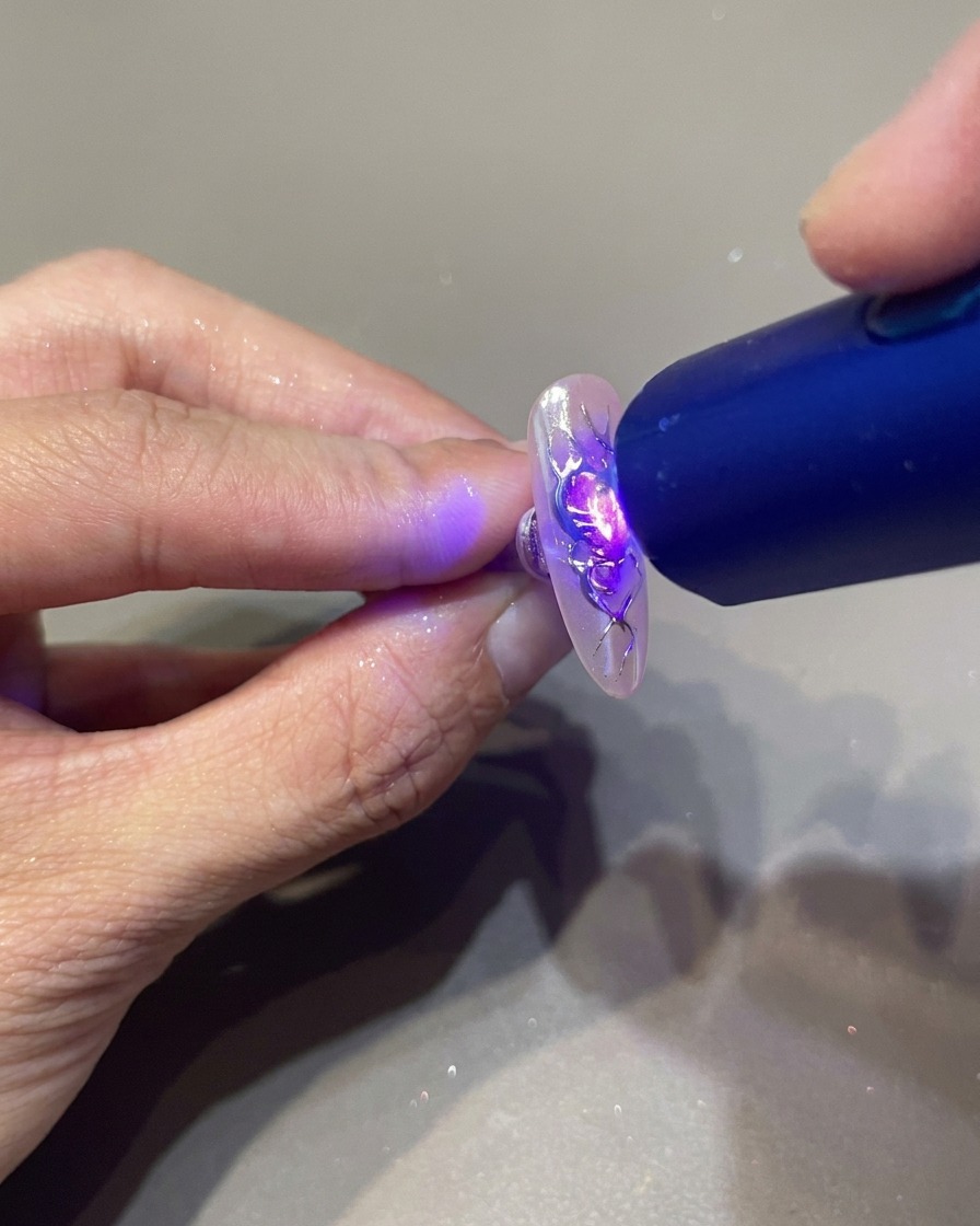 Eine tragbare UV-Lampe härtet die 3D-Geldetails auf einem Flammen-Herz-Design aus.