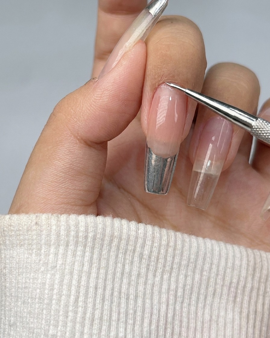Ein Nagel, dessen French-Spitze mit glänzendem silbernem Metallic-Gel ausgefüllt wird.