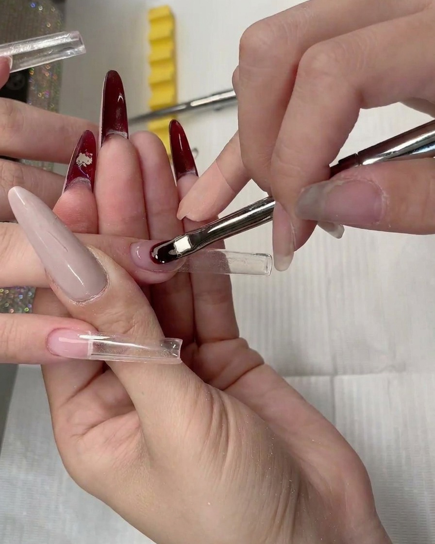 Nahaufnahme einer klaren Nagelverlängerungsschablone, die unter dem natürlichen Nagel platziert wird.