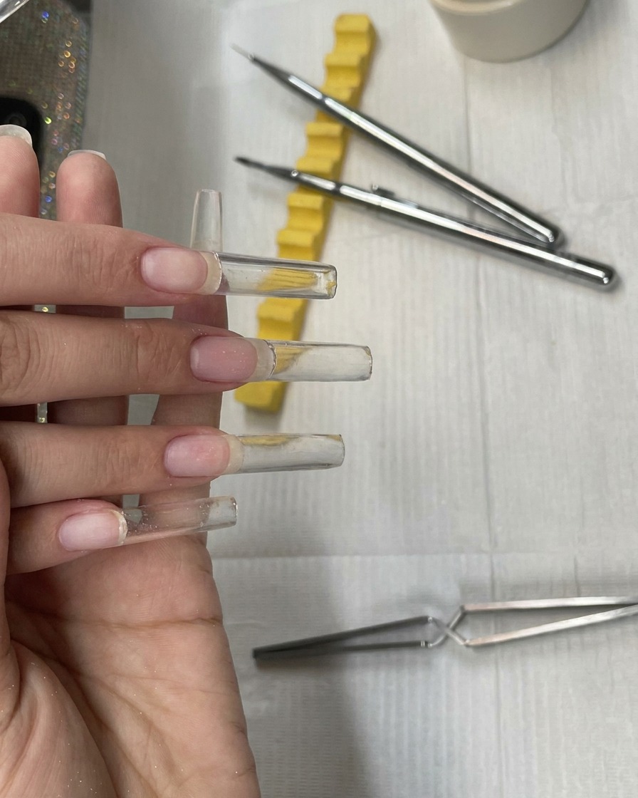 Vier fertig modellierte, nicht ausgehärtete klare extra-lange quadratische Gelnägel.