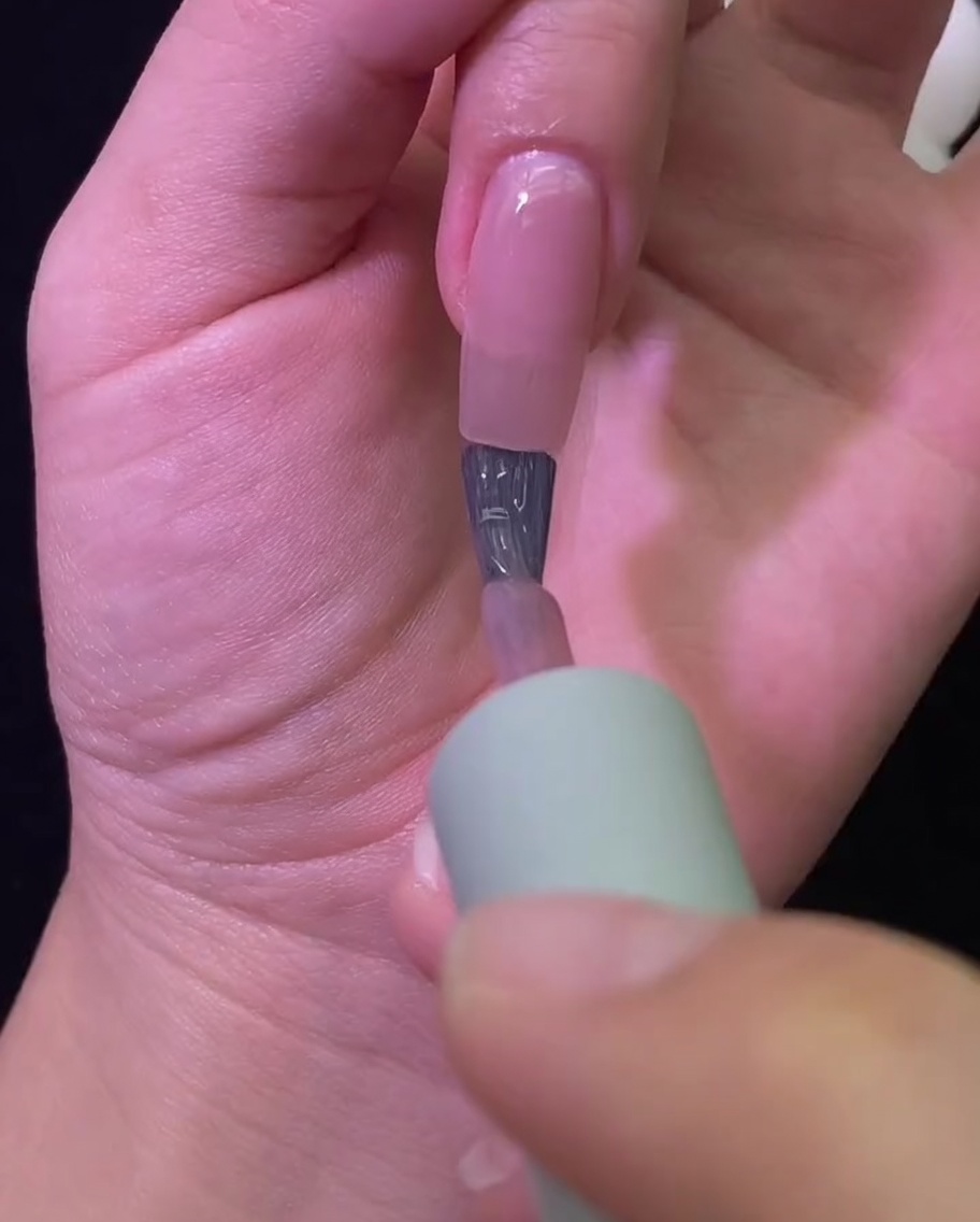 Eine Hand, die für den Aushärtungsvorgang in einer professionellen UV/LED-Nagellampe liegt.