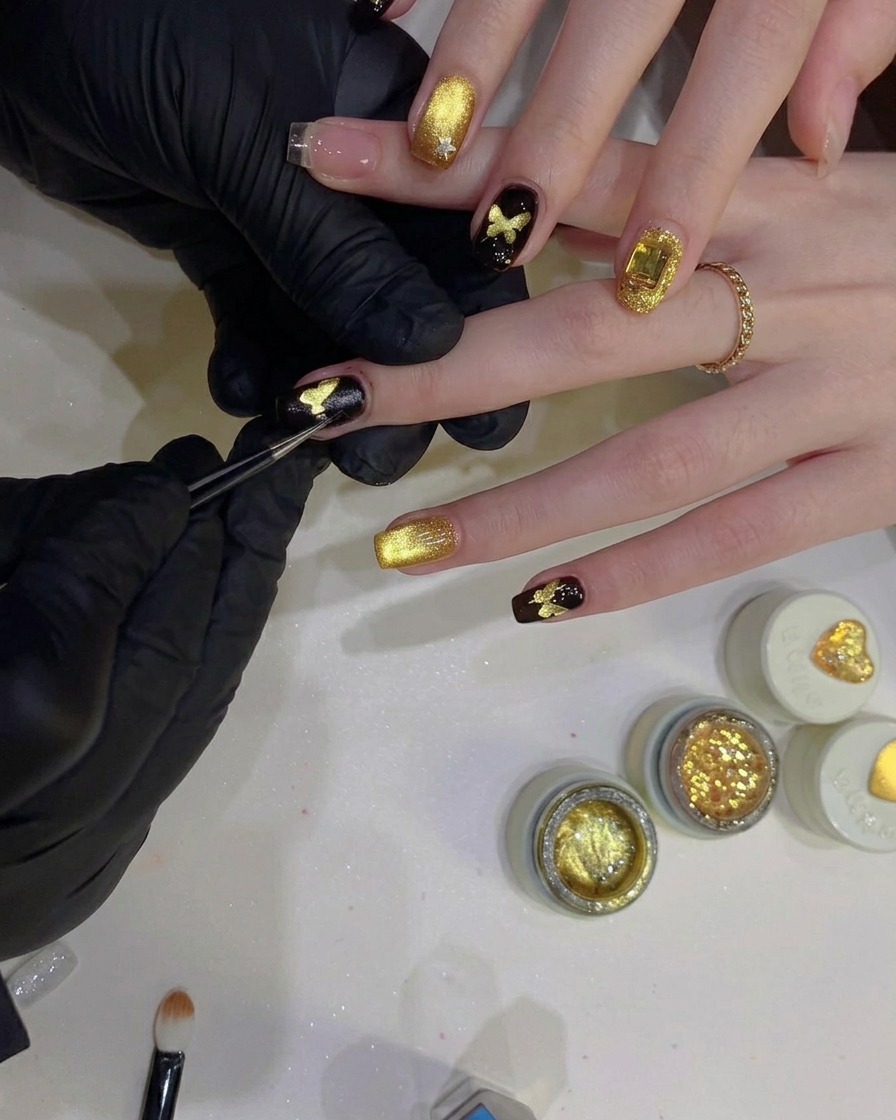 Eine Präzisionspinzette zieht eine schmetterlingsförmige Schablone von einem Nagel ab und enthüllt ein glitzerndes goldenes Schmetterlingsdesign unter einem schwarzen Hintergrund.