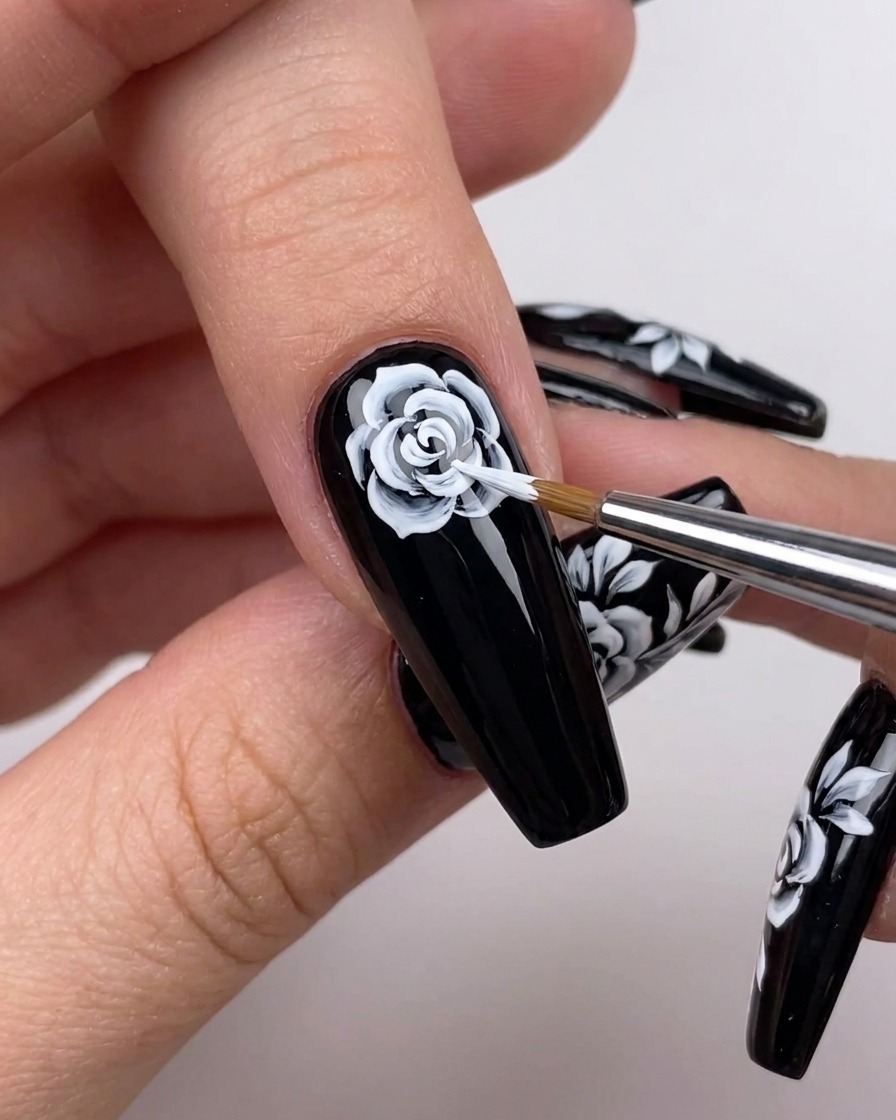 Detailansicht, wie eine Hand mit einem Pinsel weiße Linien von der Rosenmitte nach außen hin erweitert.