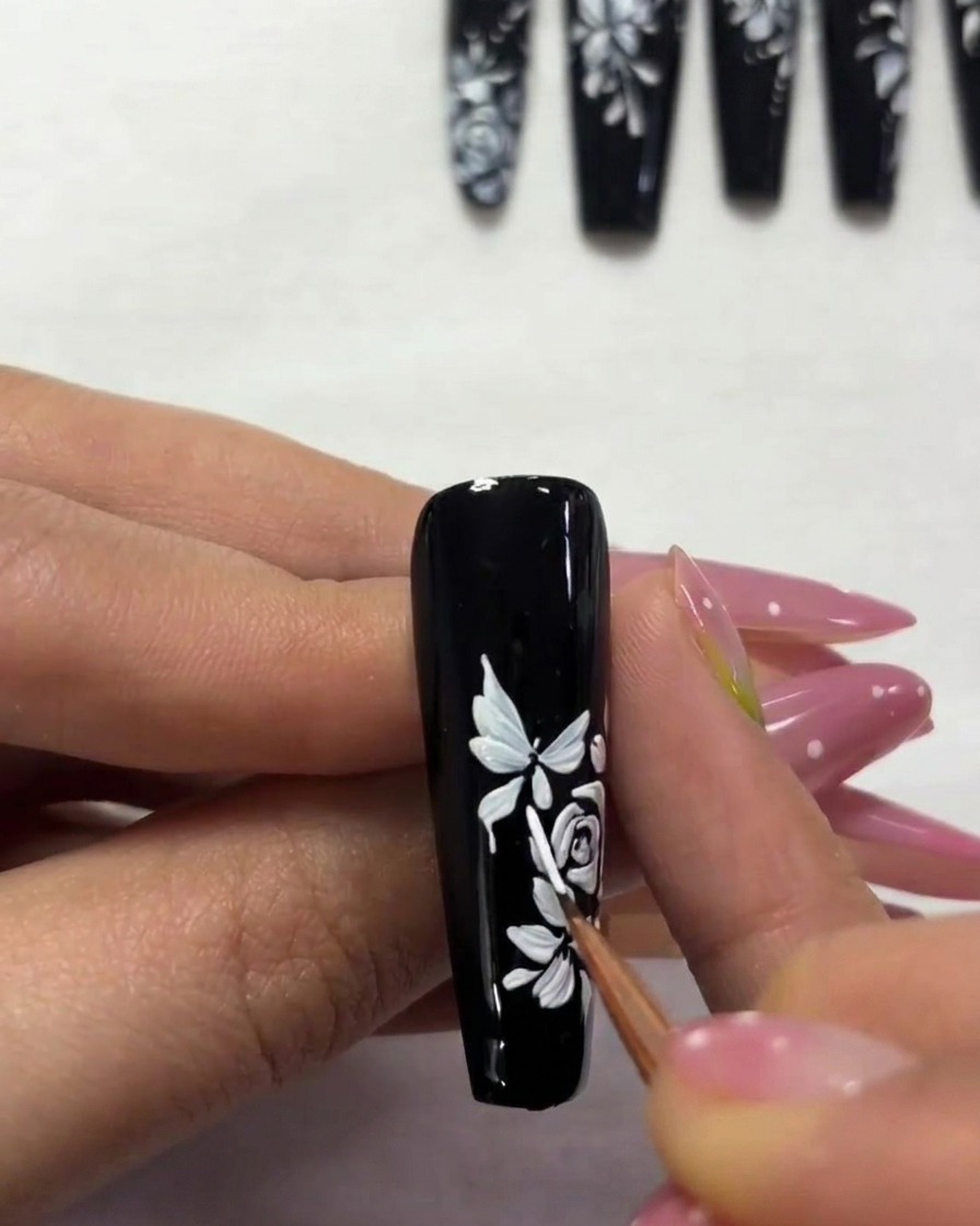 Nahaufnahme eines Nagels, auf dem ein kleinerer Schmetterling am oberen Rand gemalt wird.