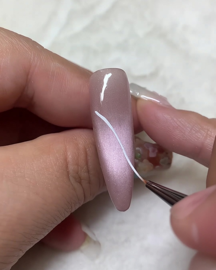 Ein feiner Pinsel fügt den diagonalen Linien gebogene Striche hinzu, um die Form der oberen Flügel zu vervollständigen.