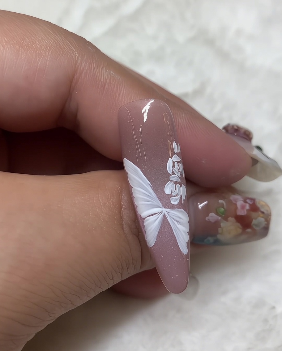 Nahaufnahme einer weißen Gelrose, neben die mit einem Fine Liner kleine, detaillierte Blätter gezeichnet werden.