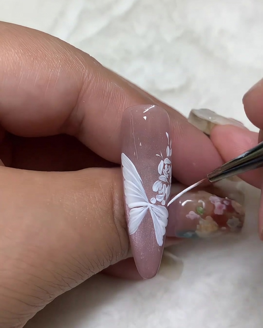 Ein Fine Liner Pinsel zieht die äußeren Ränder eines weißen Schmetterlingsflügels nach, um die Details zu verfeinern.