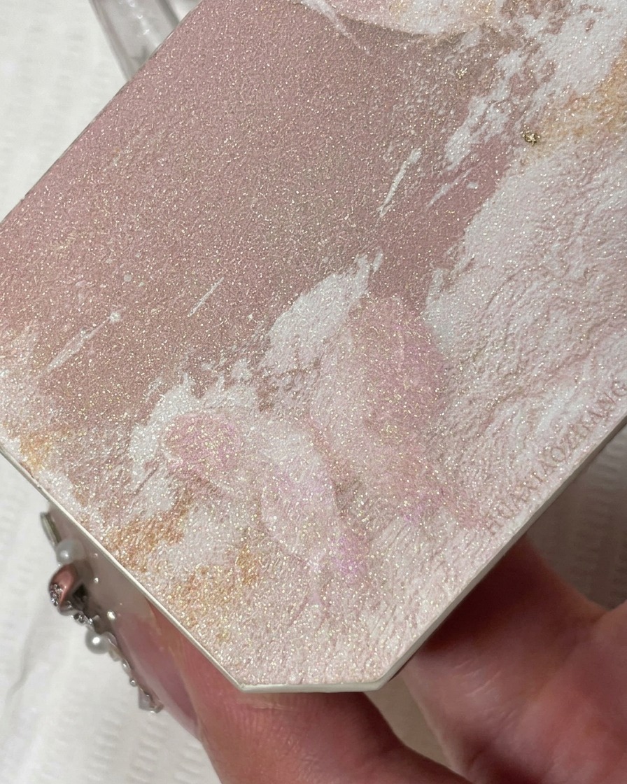 Ein feiner Liner-Pinsel trägt funkelndes Champagner-Glitzergel auf die Nagelspitze auf.