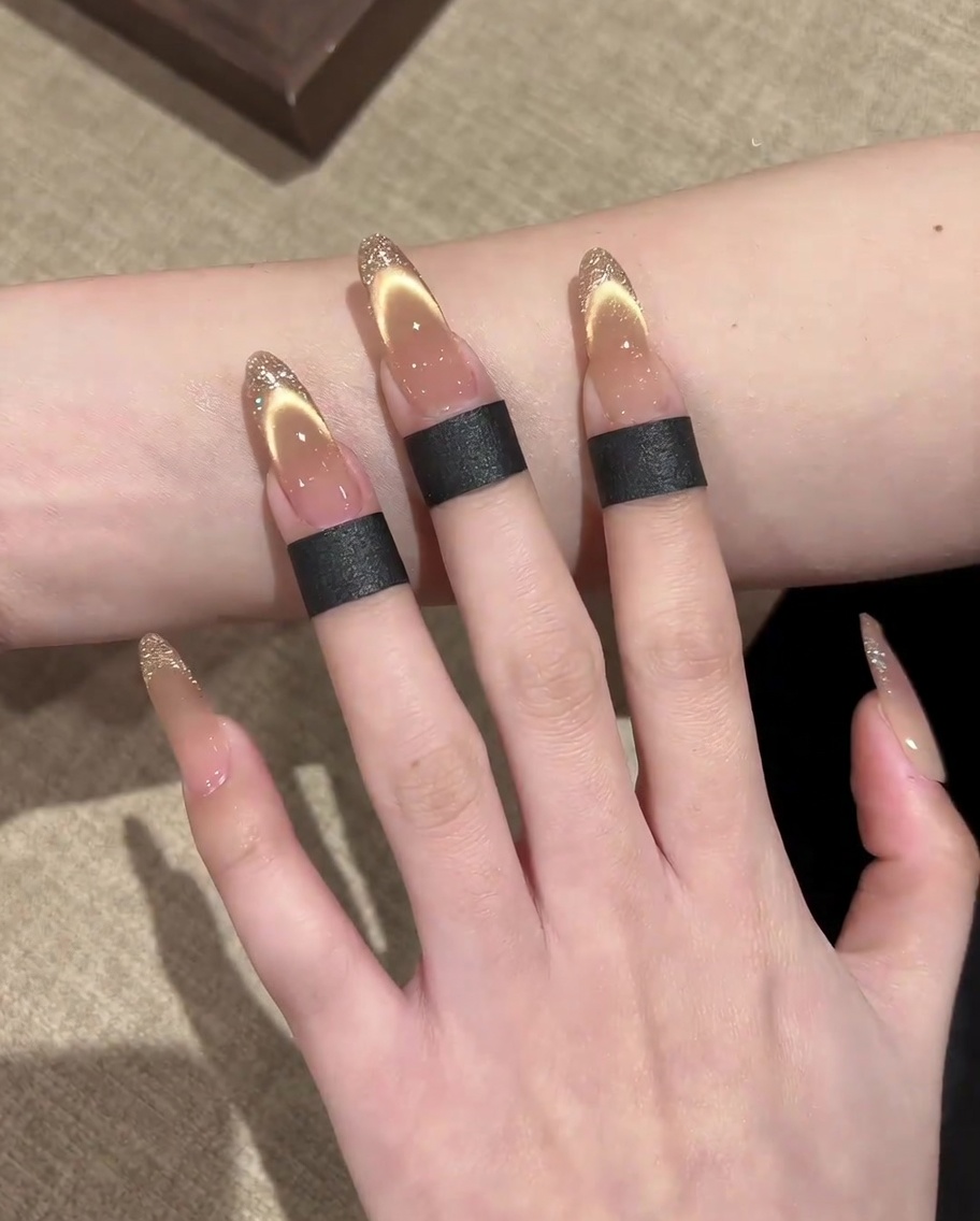 Ein Pinsel, der ein schimmerndes, magnetisches Gold-Cat-Eye-Gel auf den Nagel aufträgt.