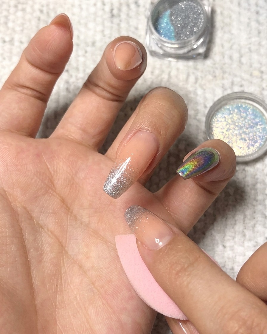 Holografisches Puder auf die Spitze eines manikürten Ringfingers tupfen.