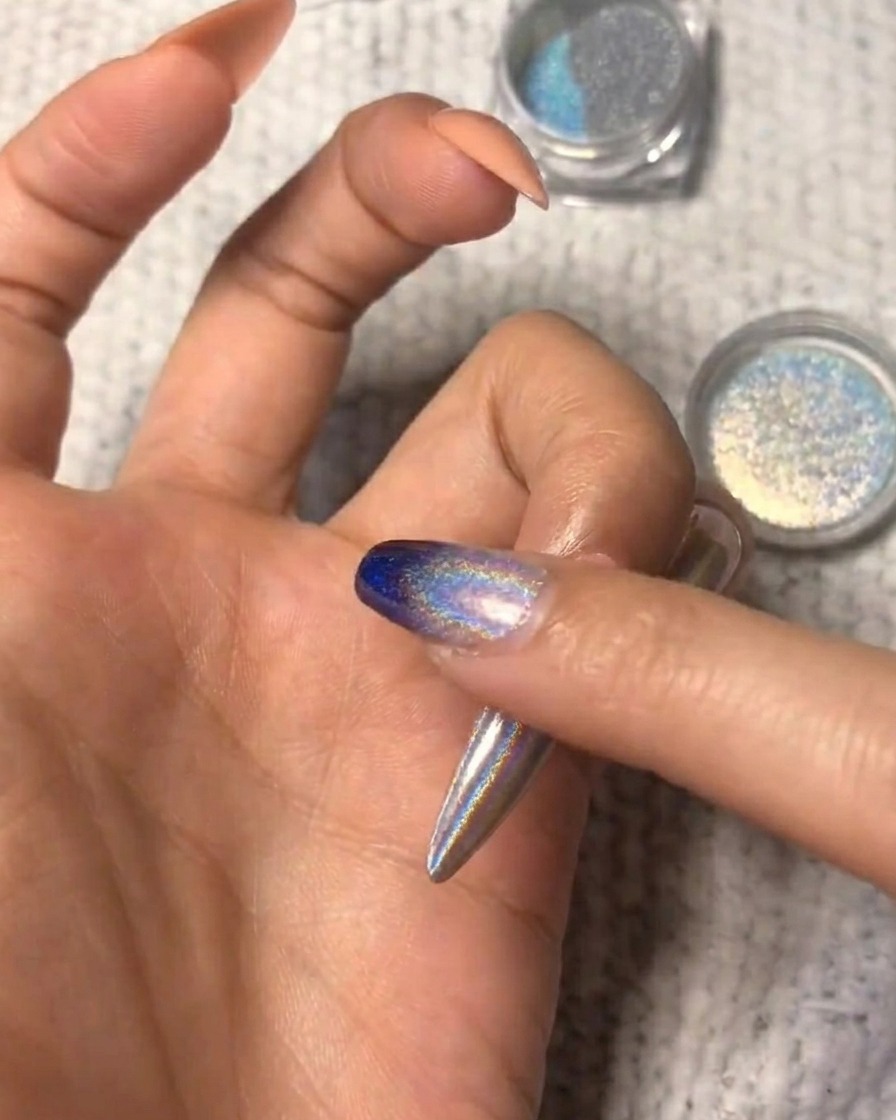 Nahaufnahme des holografischen Puders, das für einen Ombré-Look auf dem Nagel verblendet wird.