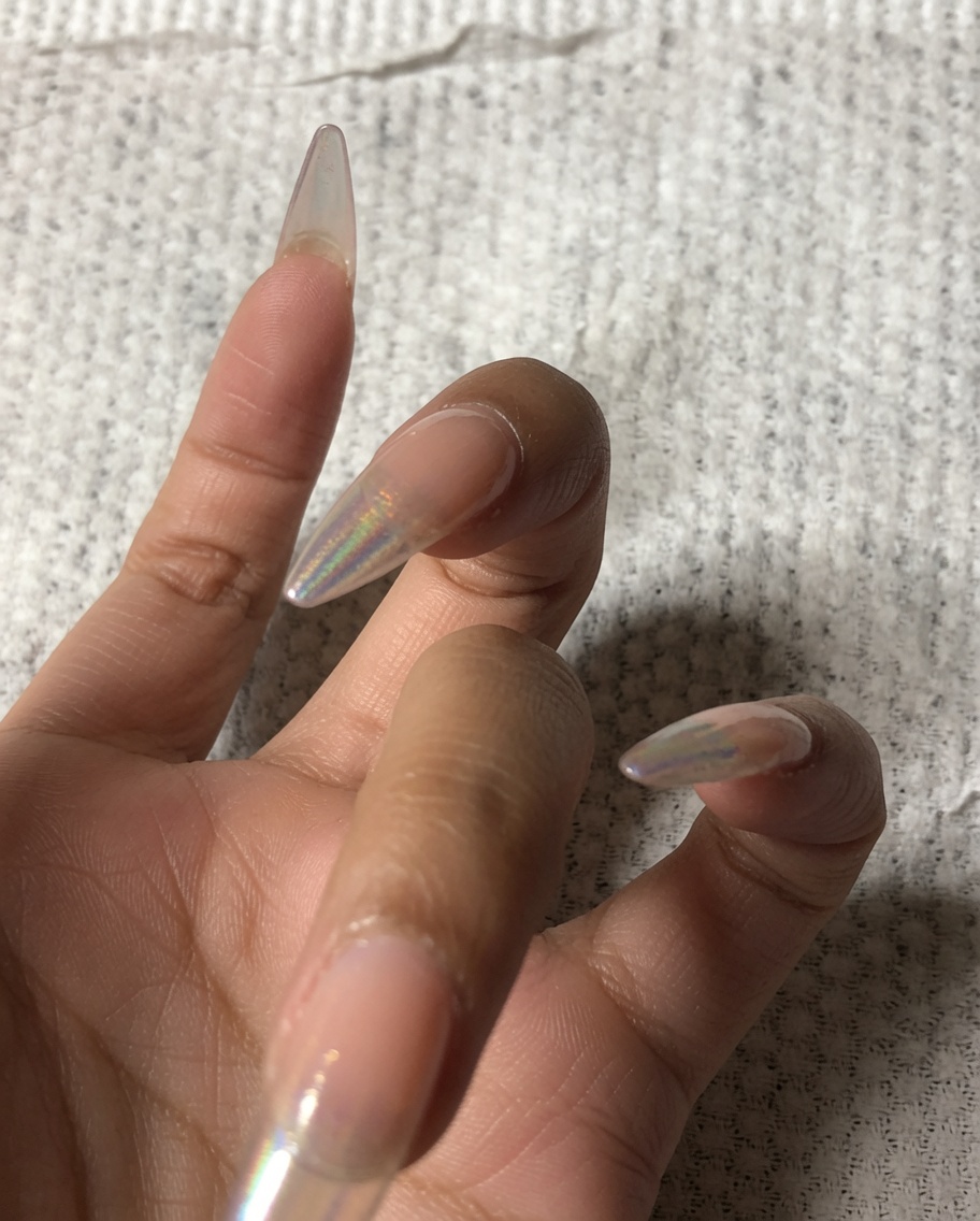 Eine Hand benutzt einen kleinen Buffer, um den vorderen Rand eines Fingernagels zu feilen.