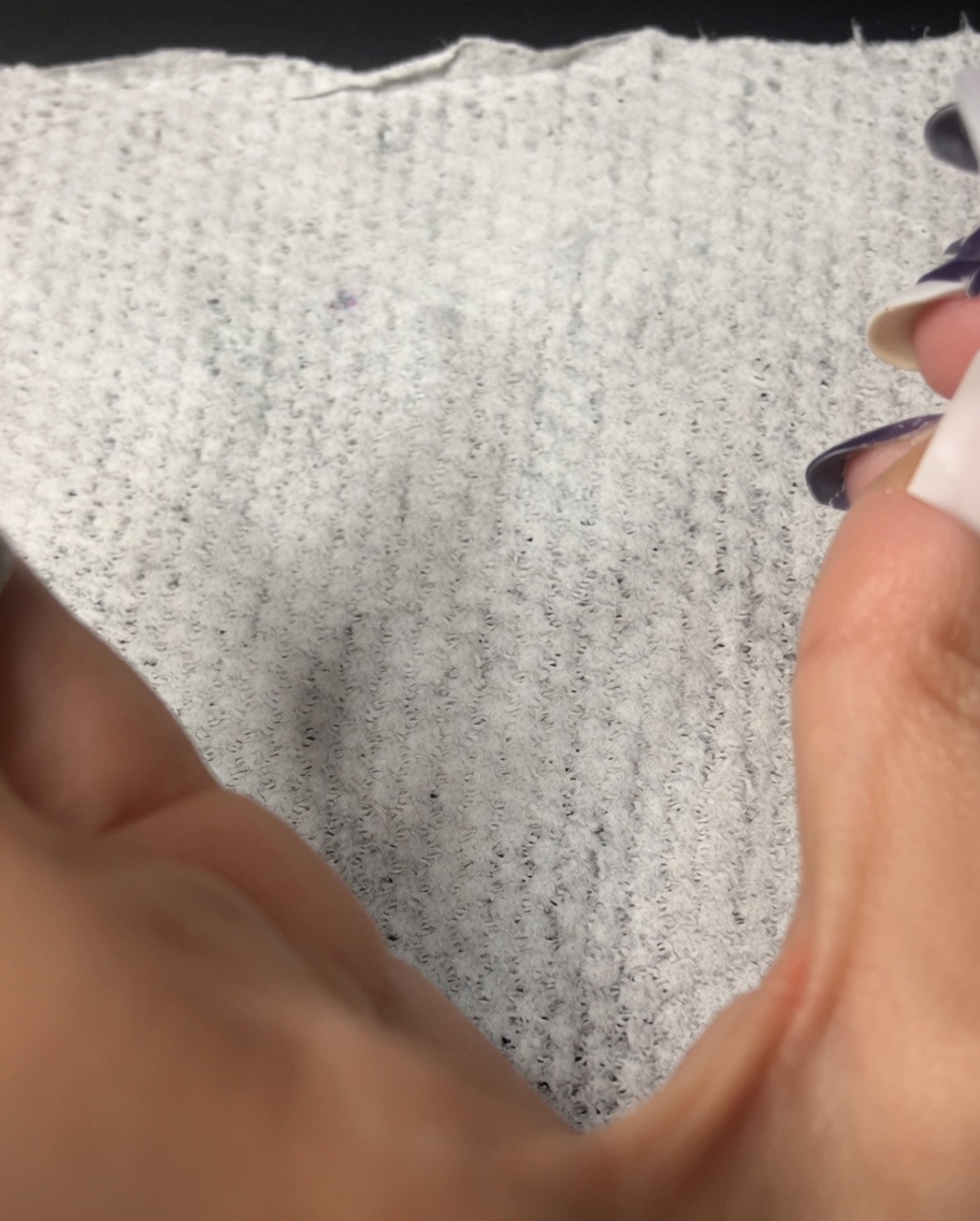 Ein fusselfreies Tuch wird verwendet, um die Oberfläche eines manikürten Fingernagels zu reinigen.