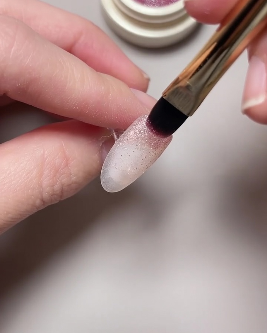 Nahaufnahme, wie ein Magnetwerkzeug über feuchtem Cat-Eye-Gel gehalten wird, um ein Nebelmuster zu formen.