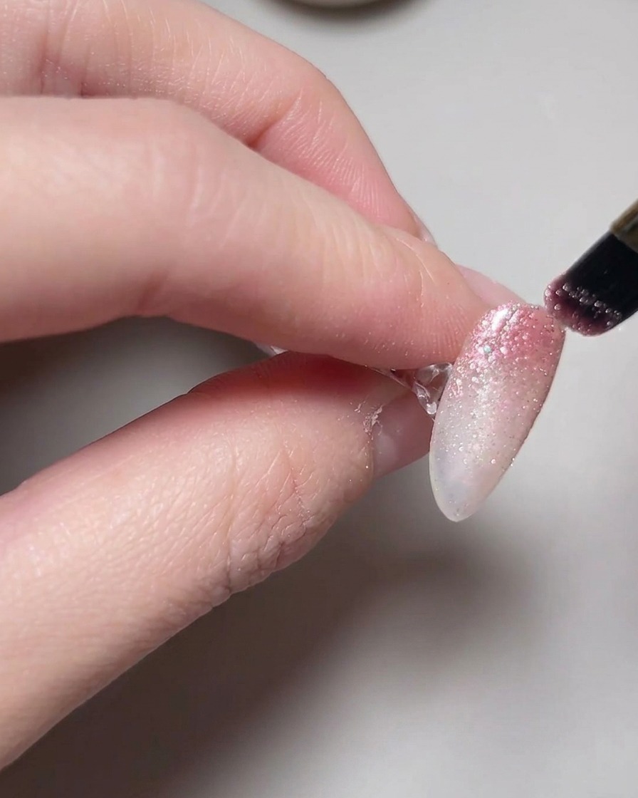 Eine Hand befindet sich in einer Lampe, während Cat-Eye-Gel auf den Nägeln aushärtet.
