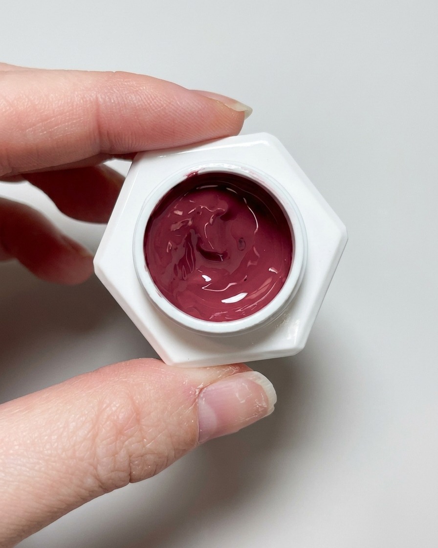Ein Pinsel trägt einen klaren, glänzenden Topcoat auf das fertige Cat-Eye-Design auf.