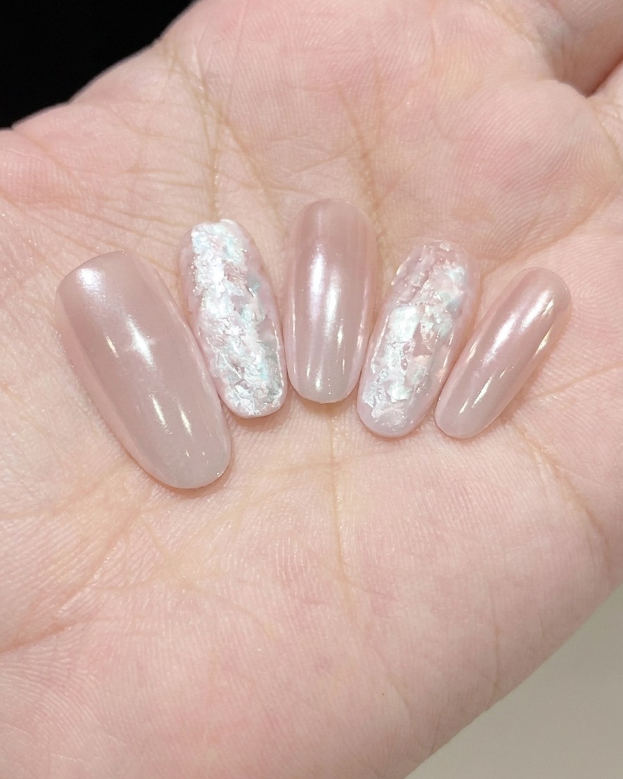 Ein Pinsel trägt eine dünne Schicht schimmernden Fine Pearl Glue auf einen Nagel auf.