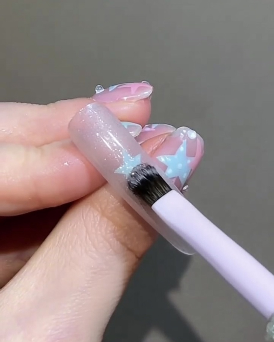 Ein kleiner flacher Pinsel tupft und glättet sanft das nasse Cat-Eye-Gel auf dem Nagel.